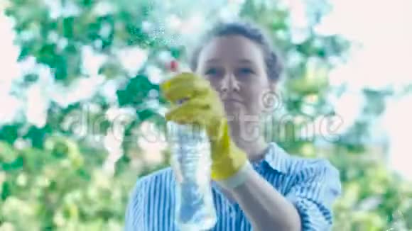 穿着衬衫的微笑女士在窗户上喷洒洗涤剂和擦拭物视频的预览图