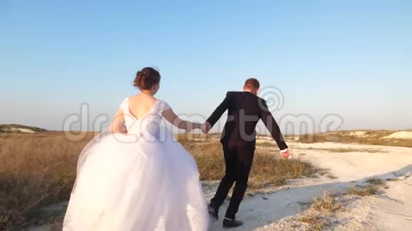 快乐的女孩和男人牵着手在路上奔跑在蜜月旅行中恋爱的情侣一对已婚夫妇度假视频的预览图