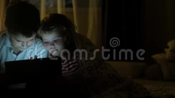 兄妹俩坐在毯子上在平板上看动画片视频的预览图