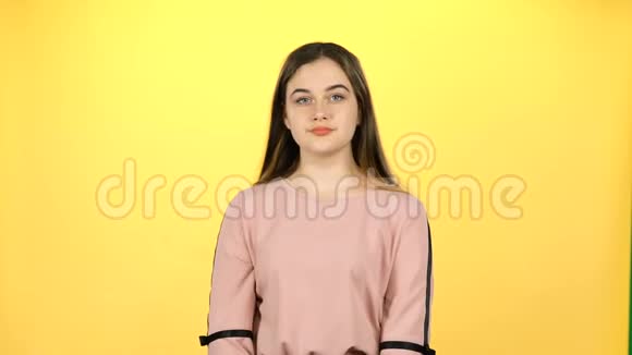 年轻的女孩用双手挥舞着黄色的背景视频的预览图