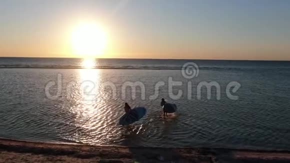 年轻的女士们正从海滩上进入水中阳光的反射视频的预览图