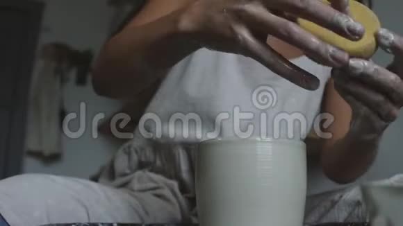 女性陶工用湿海绵成型湿粘土壶视频的预览图