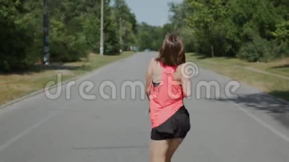 可爱的白种人女孩戴着耳机在公园里跳舞布鲁内特女人在听音乐女孩微笑着玩得开心你好视频的预览图