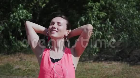 年轻性感迷人的女孩戴着耳机跳舞唱歌苗条的女人在公园里听音乐女孩站在视频的预览图