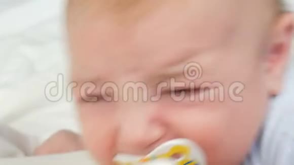 两个月大的新生儿用嘴里的奶嘴大声哭泣儿童面部近景视频的预览图