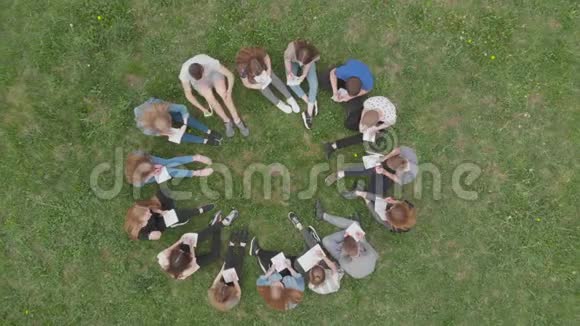 一群学生坐在一个圆圈里在草地上看书视频的预览图