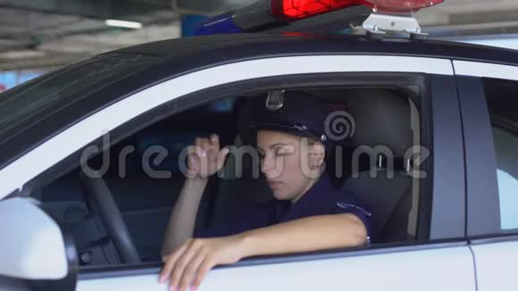 疲惫的女警察摘下帽子坐在警车里精疲力竭的工作视频的预览图