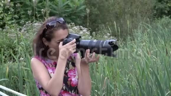 夏日日落时分一位女摄影师在公园里用长焦镜头拍摄一架专业相机视频的预览图