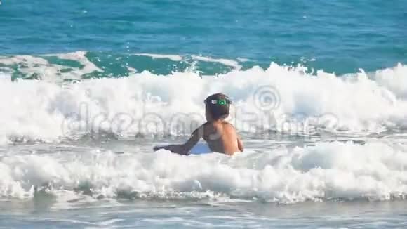 小男孩在冲浪板上跳入海浪中视频的预览图