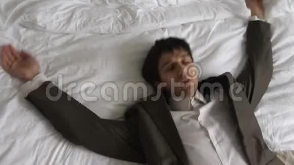 穿西装的商人躺在床上辛苦工作后需要休息视频的预览图