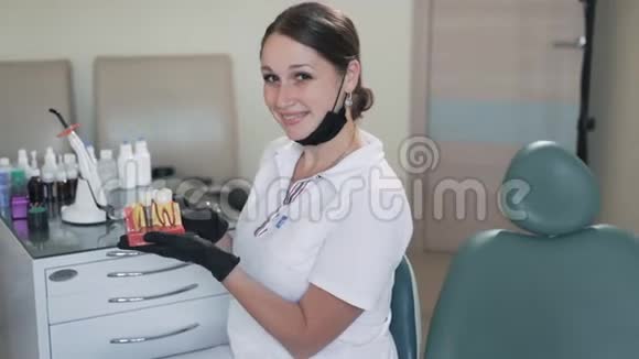 漂亮的女牙医对着镜头微笑手里拿着牙齿模型动作缓慢视频的预览图