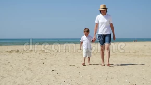 妈妈和她的儿子正牵着手沿着沙滩向大海走去视频的预览图