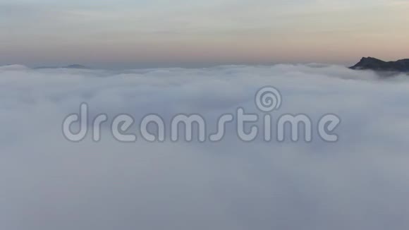 日落时间浓雾笼罩着海岸从云层上方起飞向上升起俯瞰全景视频的预览图