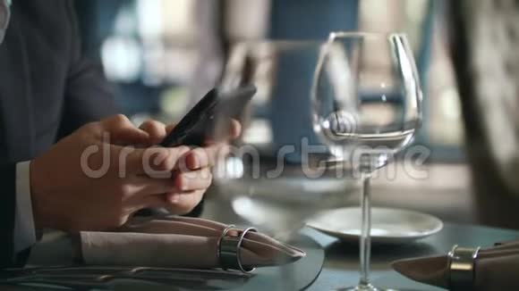 男性手在餐厅桌上打电话商人使用智能手机视频的预览图