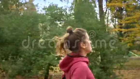 美丽的女人长发在秋天公园慢跑侧视视频的预览图