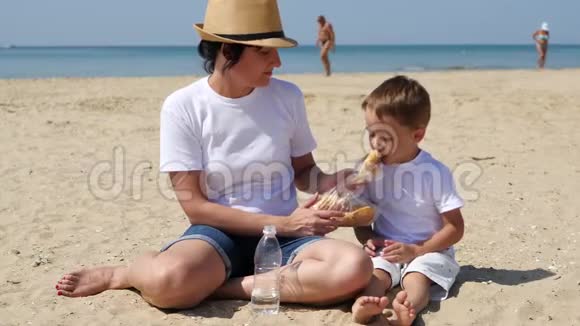 妈妈在沙滩上给孩子吃汉堡视频的预览图