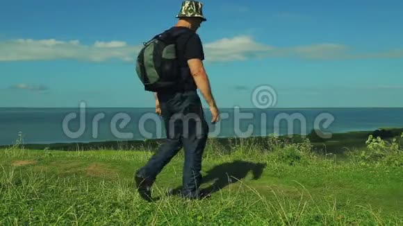 背着背包的人站在山的边缘欣赏着湖的景色射击射击视频的预览图