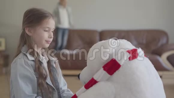 肖像可爱的女孩玩玩具北熊给他戴上皇冠她的孪生兄弟跳在沙发上视频的预览图