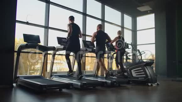 一群人在健身房的跑步机上跑步进行有氧运动男人和女人一起训练视频的预览图