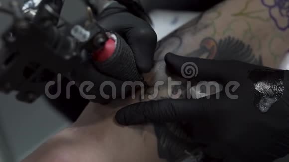 一个纹身艺术家的特写在一个男人腿上纹身很高的分辨率专业纹身师在工作室工作特写v视频的预览图