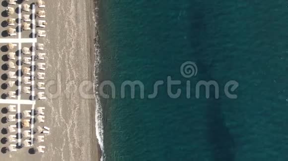 希腊圣托里尼绿松石海岸边有雨伞和遮阳伞的海滩视频的预览图