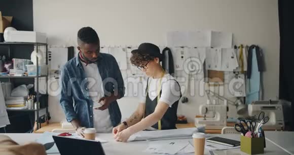 时装设计师男人和女人用布料和智能手机工作视频的预览图