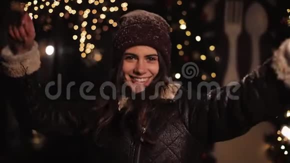 穿着冬装的漂亮微笑的女孩高兴地看着镜头女人拿着火花跳舞站在里面视频的预览图