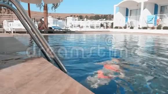 在热带度假胜地游泳池游泳的戴蓝色护目镜的女孩视频的预览图