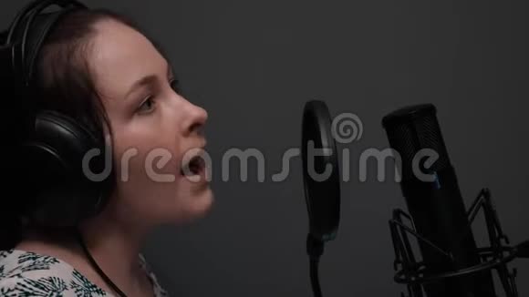 特写镜头中戴着耳机的可爱女孩正在唱歌情绪化的戏剧演唱专业声乐工作室视频的预览图