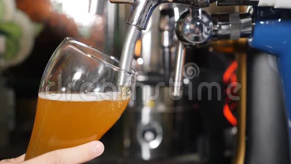 酒保把淡啤酒倒在玻璃里特写镜头啤酒被倒入玻璃中在黑色背景上制造泡沫慢动作视频的预览图