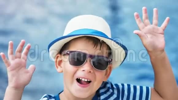 高角度特写肖像小男孩戴着太阳镜和帽子举手在户外玩得开心视频的预览图