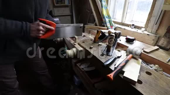 男工在棚子里的木工作台上用手锯切松木木板更高的角度在肩膀上视频的预览图