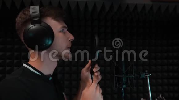 年轻英俊的白种人男孩正在准备录制歌曲戴着耳机的歌手开始在录音室唱歌视频的预览图