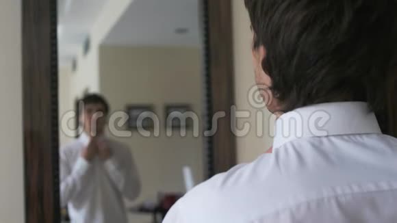 年轻英俊的男人在镜子前打扮自己视频的预览图