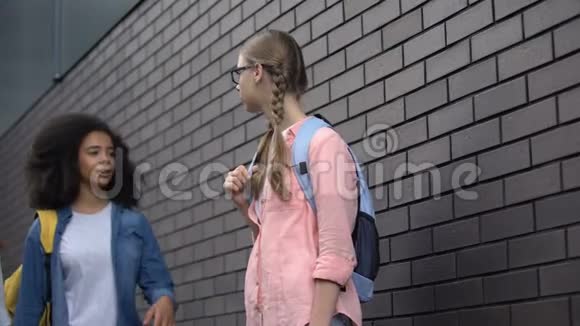 残忍的青少年用胳膊肘推着眼镜学校后院的同学视频的预览图