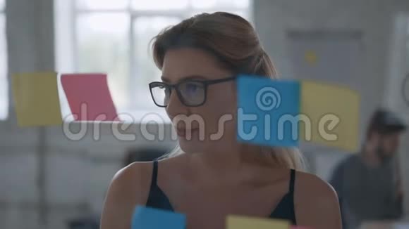 商务女性使用粘性笔记头脑风暴解决问题的策略在玻璃白板上显示解决方案视频的预览图