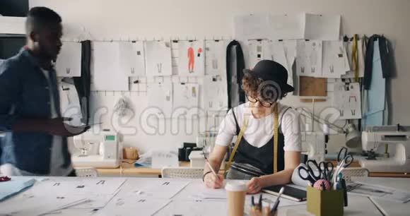 男女服装设计师在工作室中使用平板画草图视频的预览图