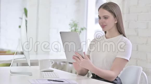 漂亮的年轻女人用平板电脑做现代办公室视频的预览图