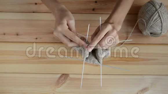 年轻妇女在木桌背景上用灰色金属针和羊毛线编织视频的预览图