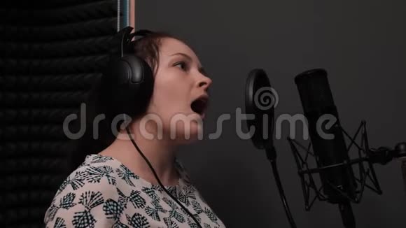 蓝眼睛唱歌的年轻迷人女孩的肖像在音乐工作室排练的女人记录设备视频的预览图