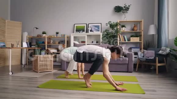 丈夫和妻子在家训练平衡手臂一起做瑜伽视频的预览图