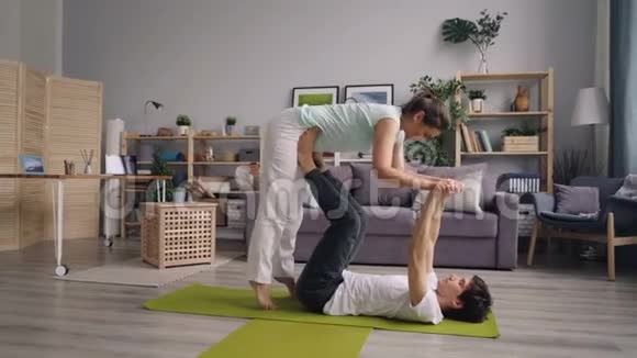 男人和女人一起做瑜伽练习男人支持平衡女孩视频的预览图