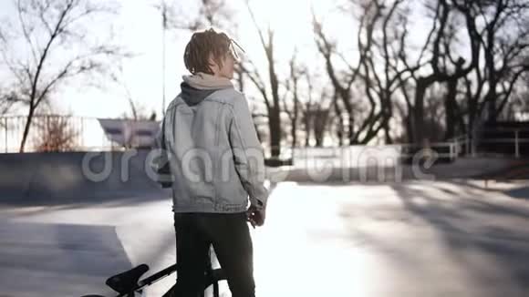 一个小男孩在溜冰公园里有一个短的可怕的家伙骑着他的BMX自行车天气晴朗侧视镜头视频的预览图