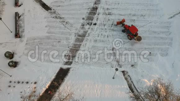 红色拖拉机清扫清除城市广场上的新鲜积雪视频的预览图