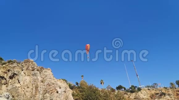 空中跳伞者在岩石底部的天空中盘旋6秒视频的预览图