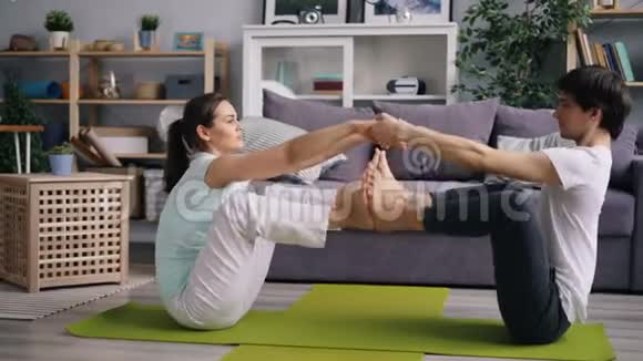 男人和女人幸福的一对夫妇在家做双手瑜伽双手合脚视频的预览图