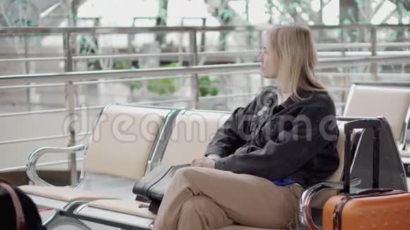 坐在机场候机室的乘客女孩正从包里拿平板电脑视频的预览图