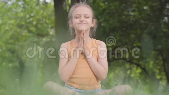 可爱的小可爱坐在草地上沉思儿童练习瑜伽夏日休闲视频的预览图