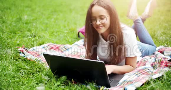 女人躺在草坪上拿着笔记本电脑视频的预览图
