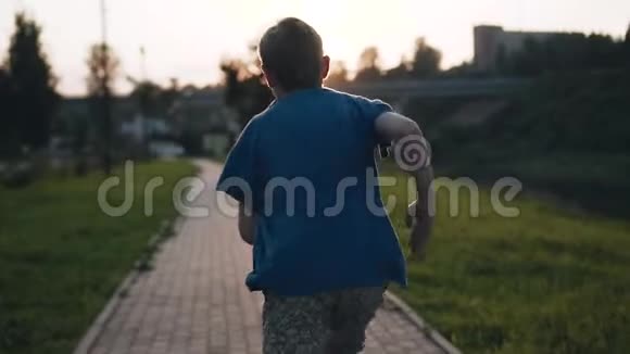 活跃的男孩在海滨跑步美丽的日落视频的预览图